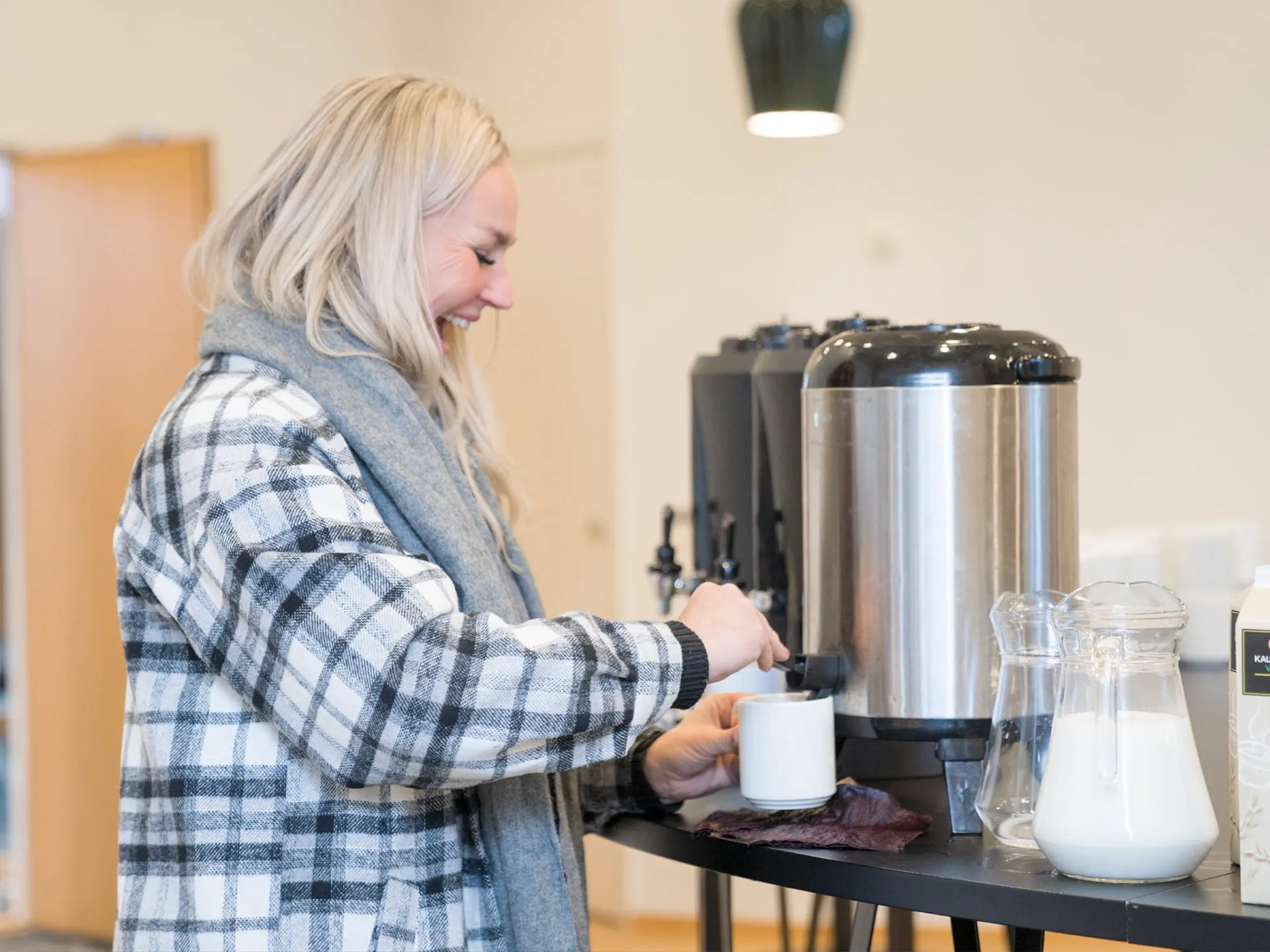 Henkilö hymyilee ottaessaan kahvia