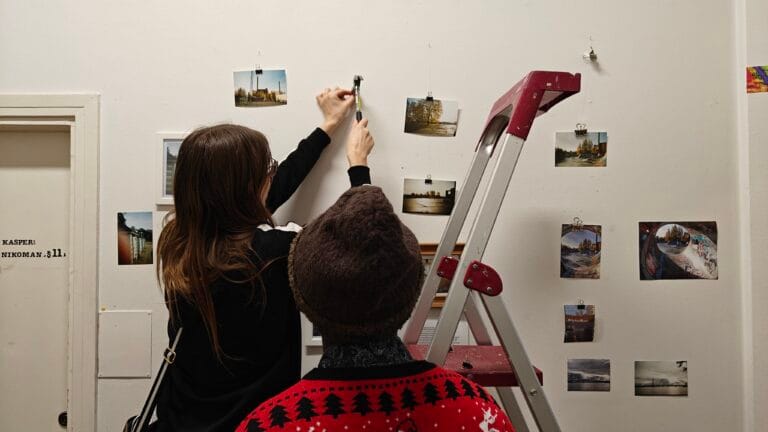 Bringing Us Together -valokuvanäyttelyn töiden asettelua seinälle.